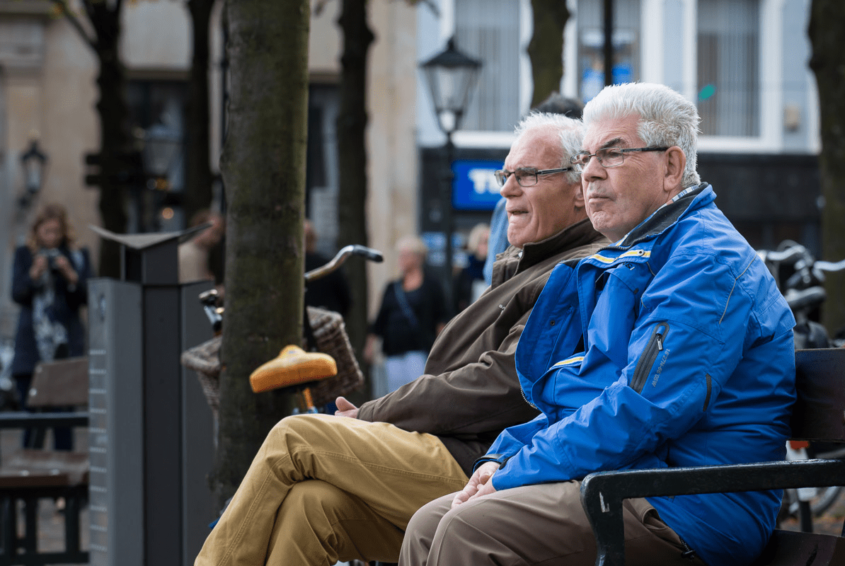 Oudere mannen op een bankje buiten in de stad (foto Ineke Linssen)