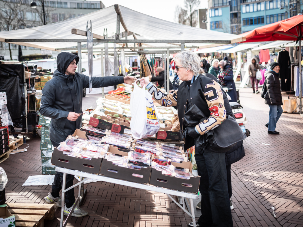 Een vrouw koopt iets bij een marktkraam.