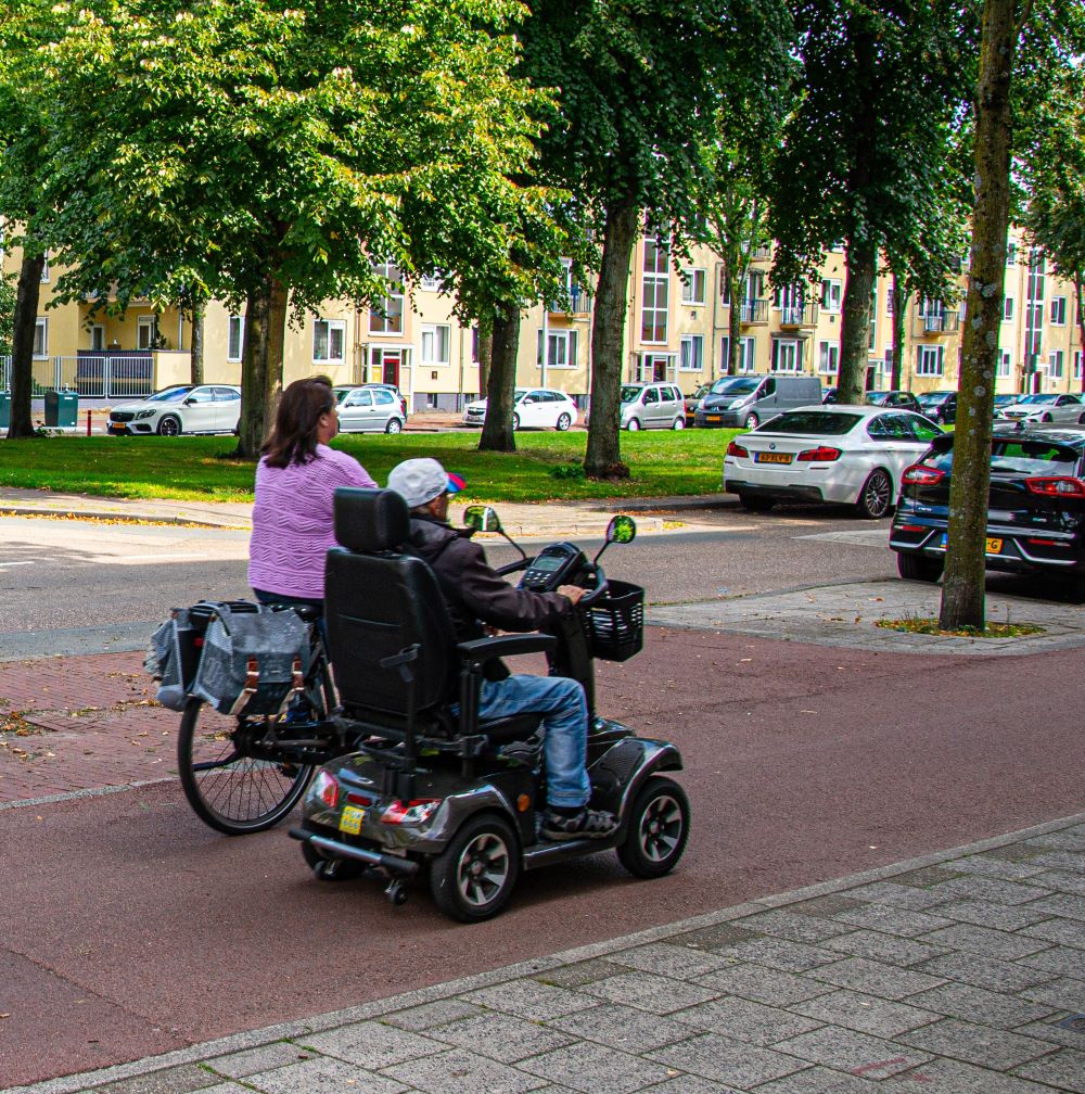 Scootmobiel en fietser in de wijk