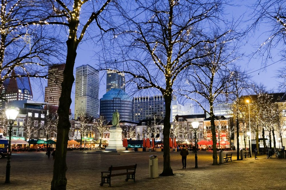 De skyline van Den Haag in de avond gezien vanaf Het Plein, versierd met kerstlampjes.